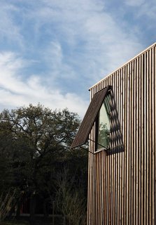 The rhythm of the slat wall (made from red cedar and stained to look prematurely weathered) is echoed in the shutter detailing on each window.