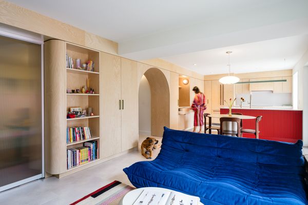 The continuous birch plywood millwork spine anchors the 1,200-square-foot apartment, concealing structural columns and ductwork while organizing storage, display, and workspace in one fluid gesture. 