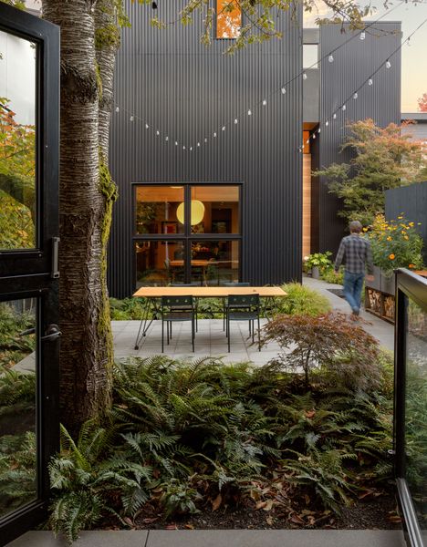 The L-shaped Nook House creates private courtyards on the 7,600-square-foot Seattle lot, now home to three structures built over 27 years. AEP Span Nu Wave corrugated siding in black requires zero maintenance, while Loewen aluminum-clad mixed grain fir windows and doors anchor the high-performance envelope.
