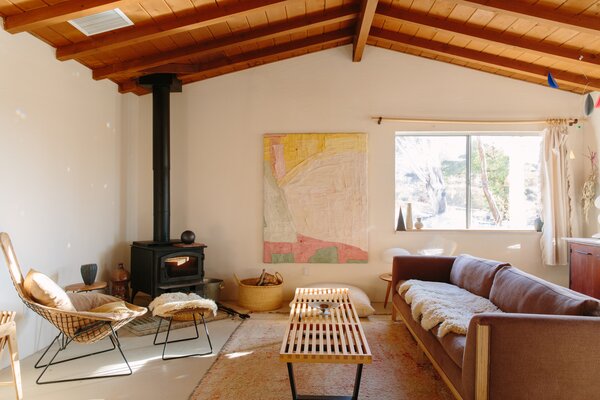 In the living room, midcentury-modern furnishings such as the Nelson Platform Bench by Herman Miller and the Bertoia Bird Chair sit alongside assorted vintage ceramics sourced by Portmans. A painting by Portmans’s daughter, Sarah Marlowe Hall, hangs on the wall near a  fireplace.