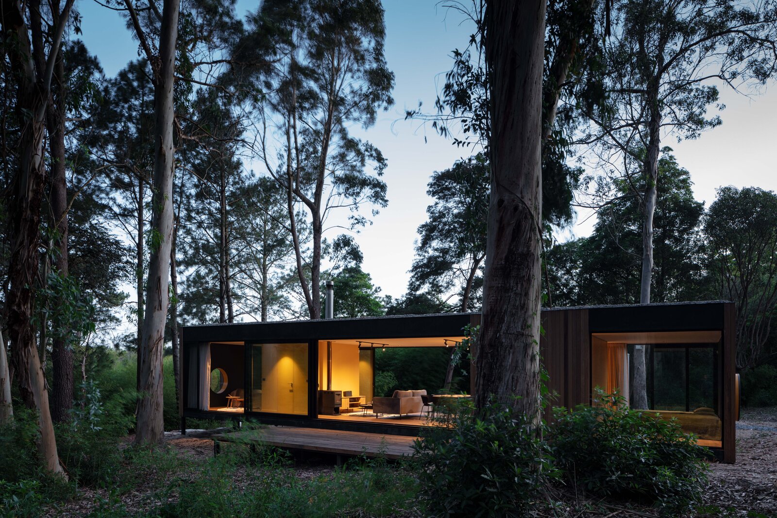 The blackened timber cladding helps the prefab to blend into the forest. The interior of the home was conceived as two blocks that house less flexible spaces like the bathroom, kitchen, and storage. This approach helped to avoid the use of interior walls, 