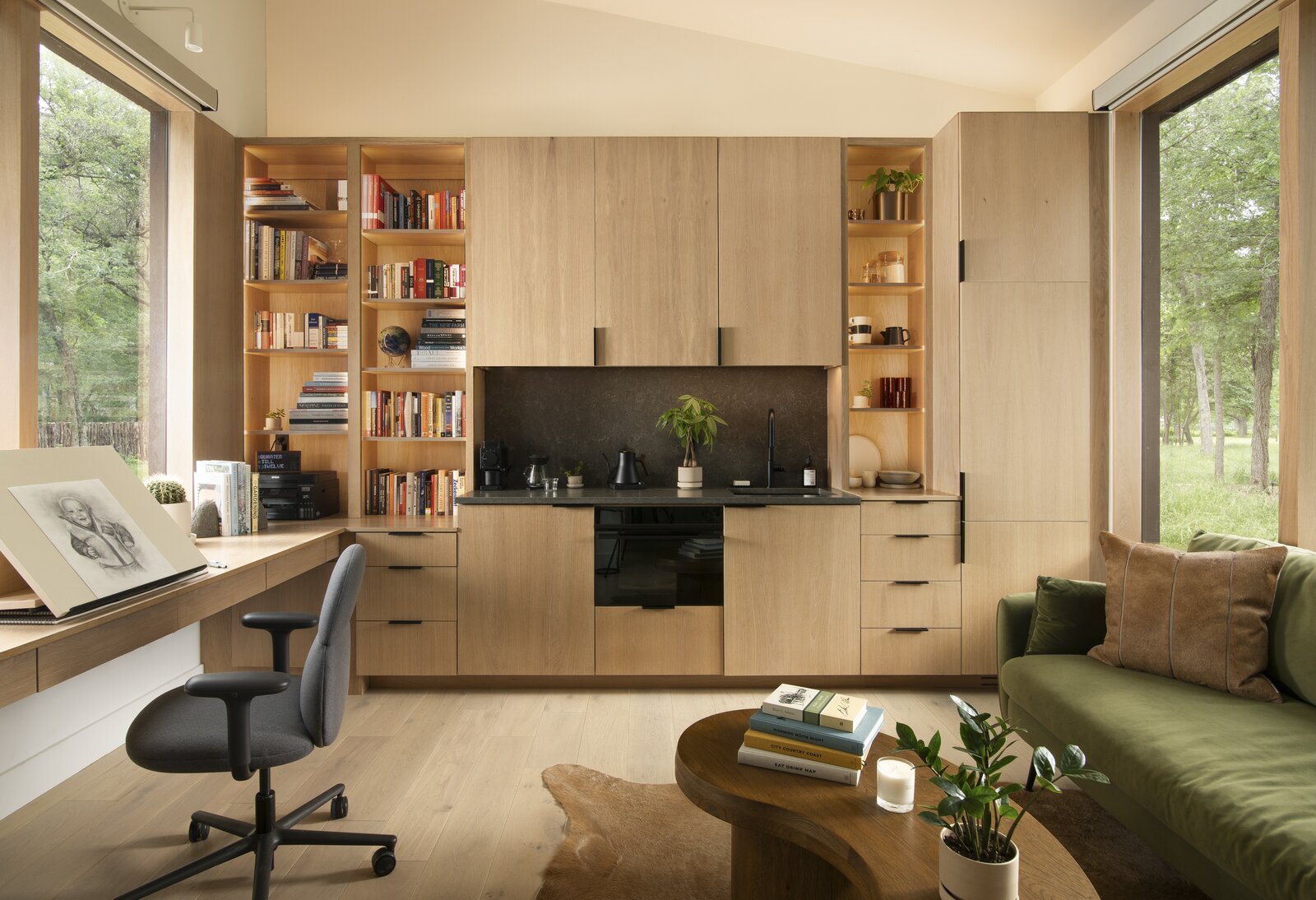 The kitchenette, pictured in the background, is outfitted with coffee supplies from Fellow and Aeropress. In the foreground is a coffee table from Crate & Barrel over a hide rug from Arhaus.  