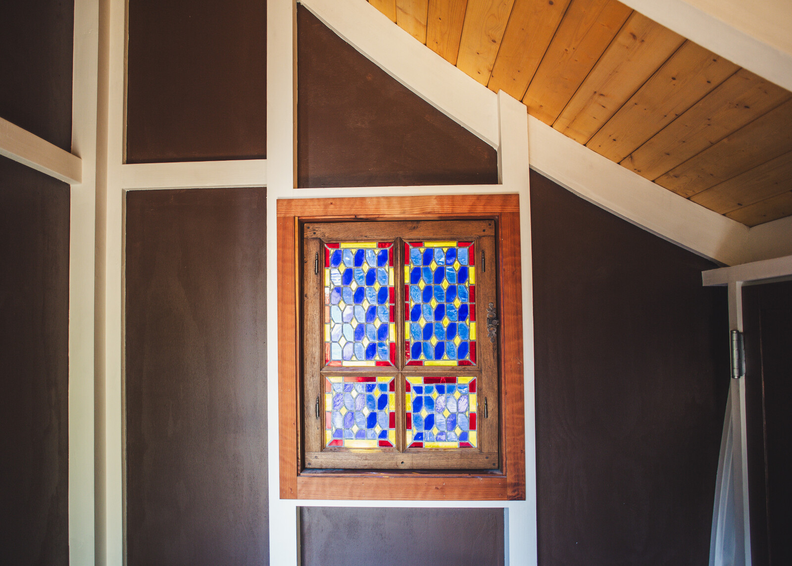 A secondhand window adds a bespoke accent to the treehouse interior. 
