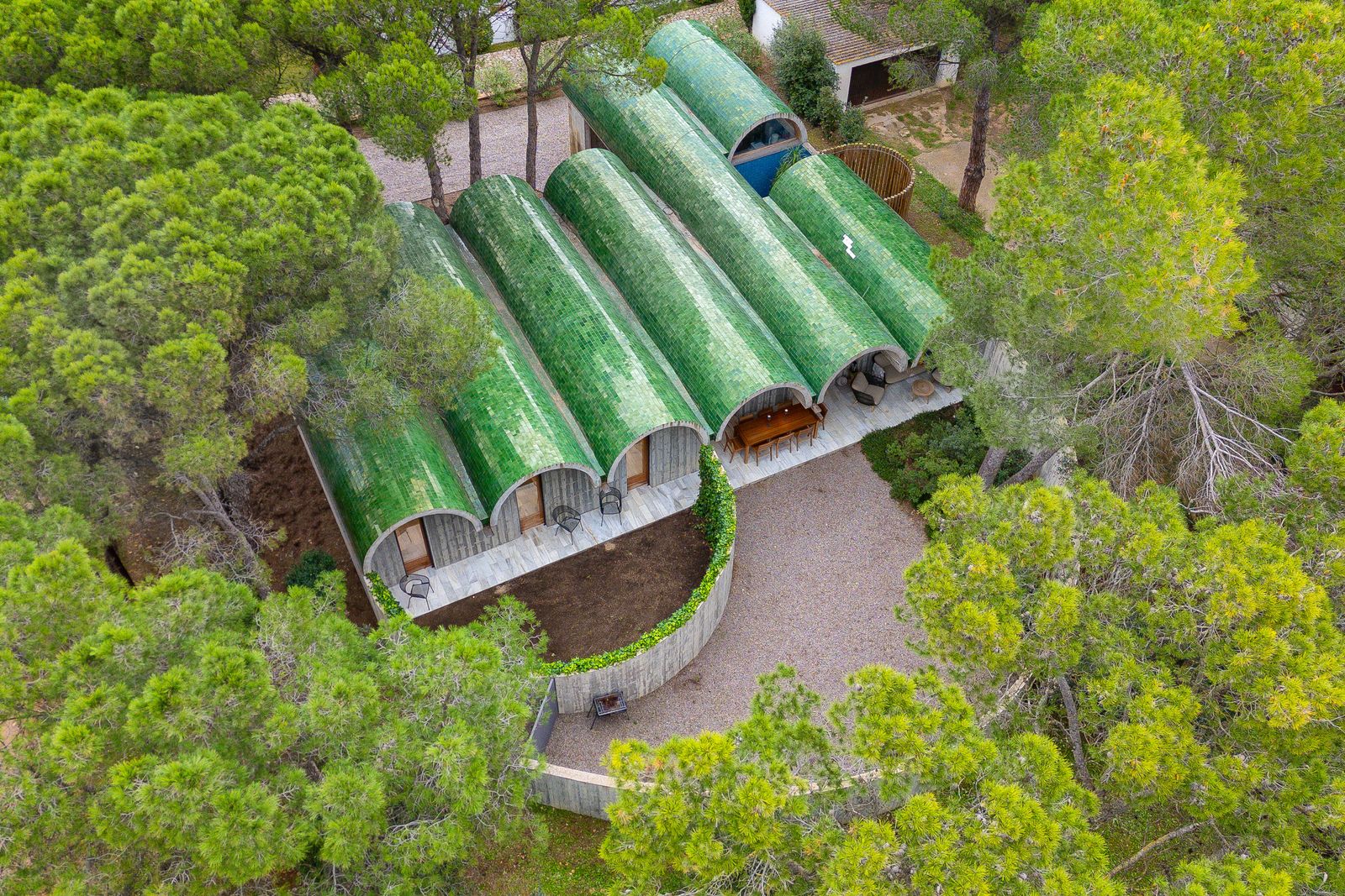 Designed by Bellafilarquitectes Studio, this residence in l’Escala features a striking curved roof clad with distinctive green tiles.