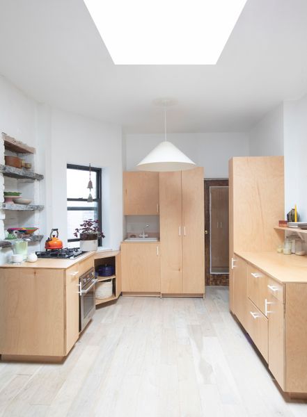 Millwork conceals everything from kitchen appliances to a washer and dryer, and even elevates the bedroom to create distinction in the small space.