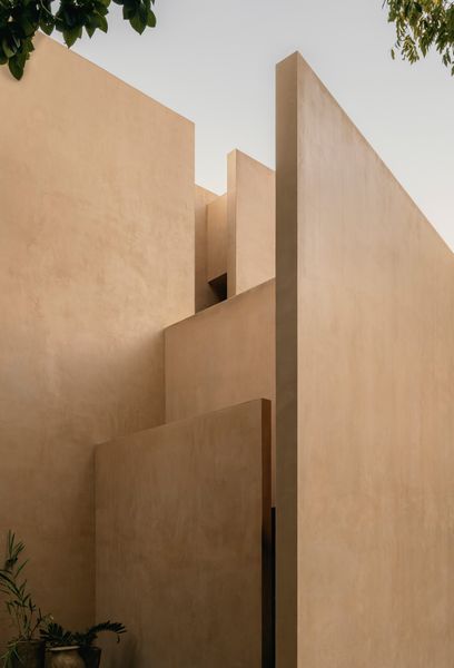 The primary materials—plaster, natural stone, and dark steel detailing—were selected for their durability, tactility, and ability to age gracefully within Tulum's tropical climate.