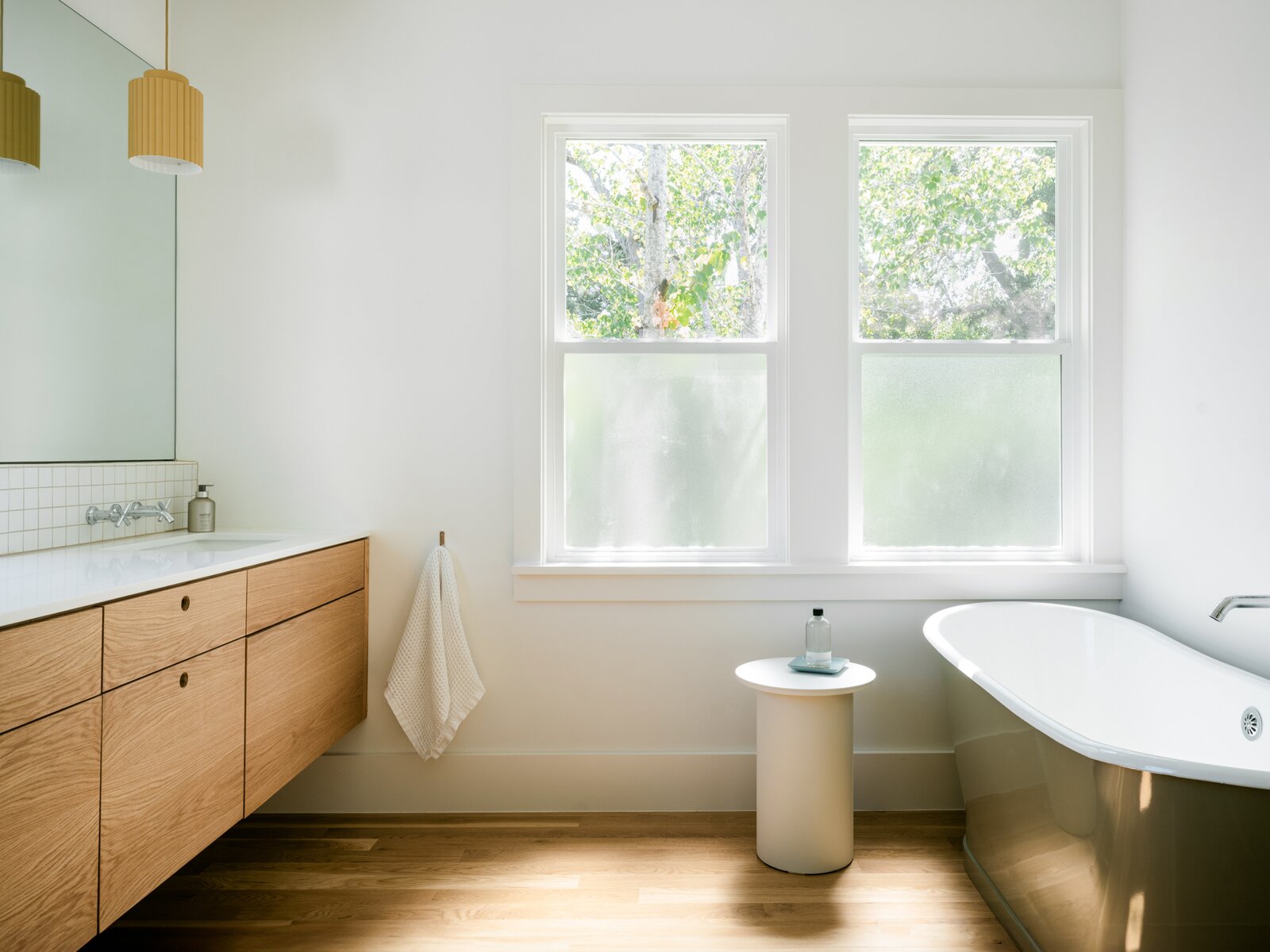 The primary bathroom includes oak cabinetry and quartzite counters. Michelle found the salvaged Rejuvenation bathtub that retails for $10,000 on Nextdoor for less than one-tenth of the price. It had a small scratch, but they opted to paint the exterior, so the imperfection didn't show in the end.