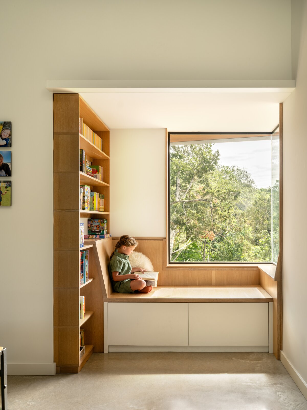 A bright reading nook captures the home's color and material palette: polished concrete floors, white walls, and oak cabinetry. The windows in the reading nook (and also the kitchen and the master bathroom) are a more expensive, frameless model.