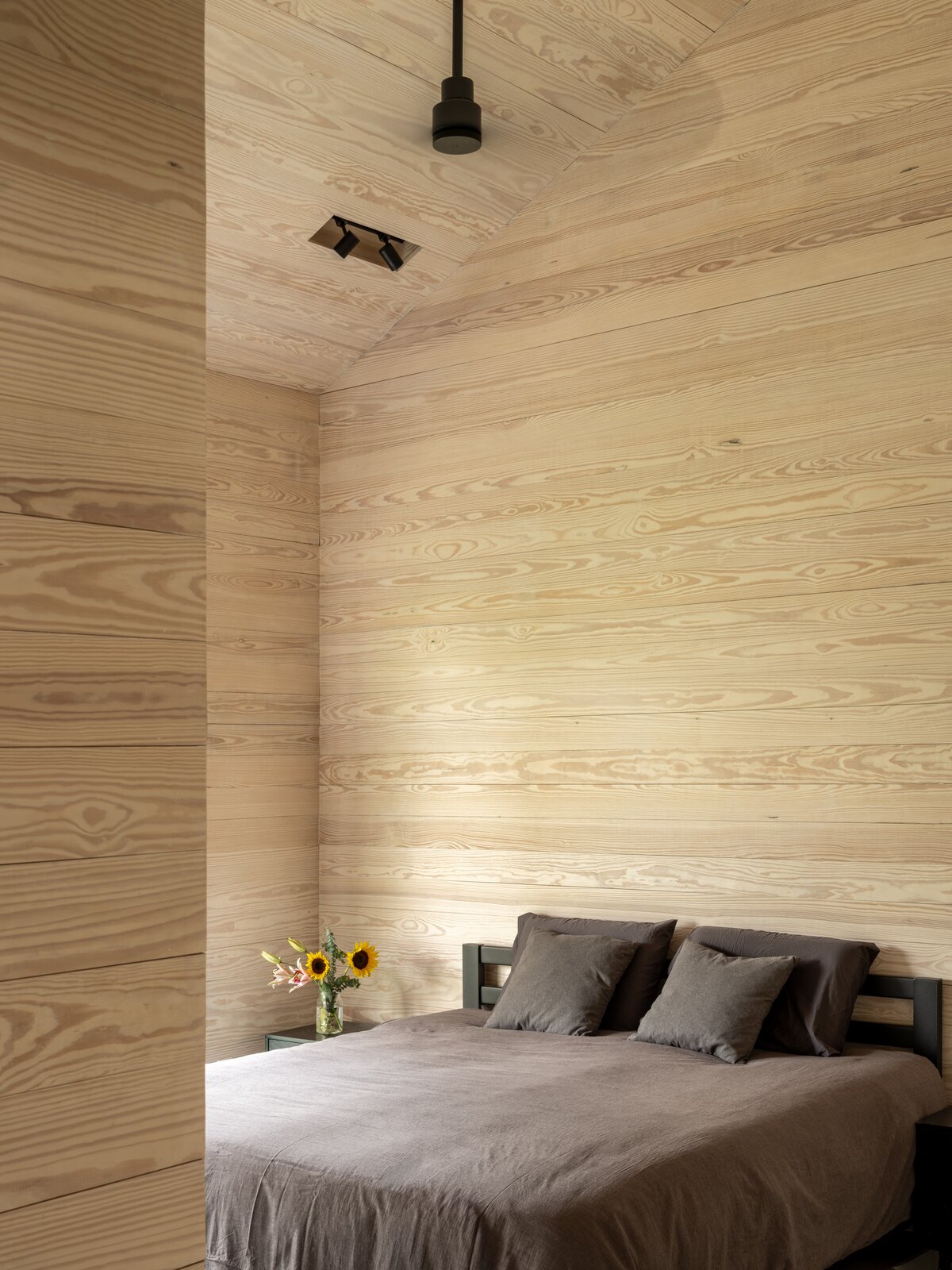 The primary bedroom has a single-material palette: pine wood. The light tone creates a relaxing backdrop for minimal, modern furniture. 
