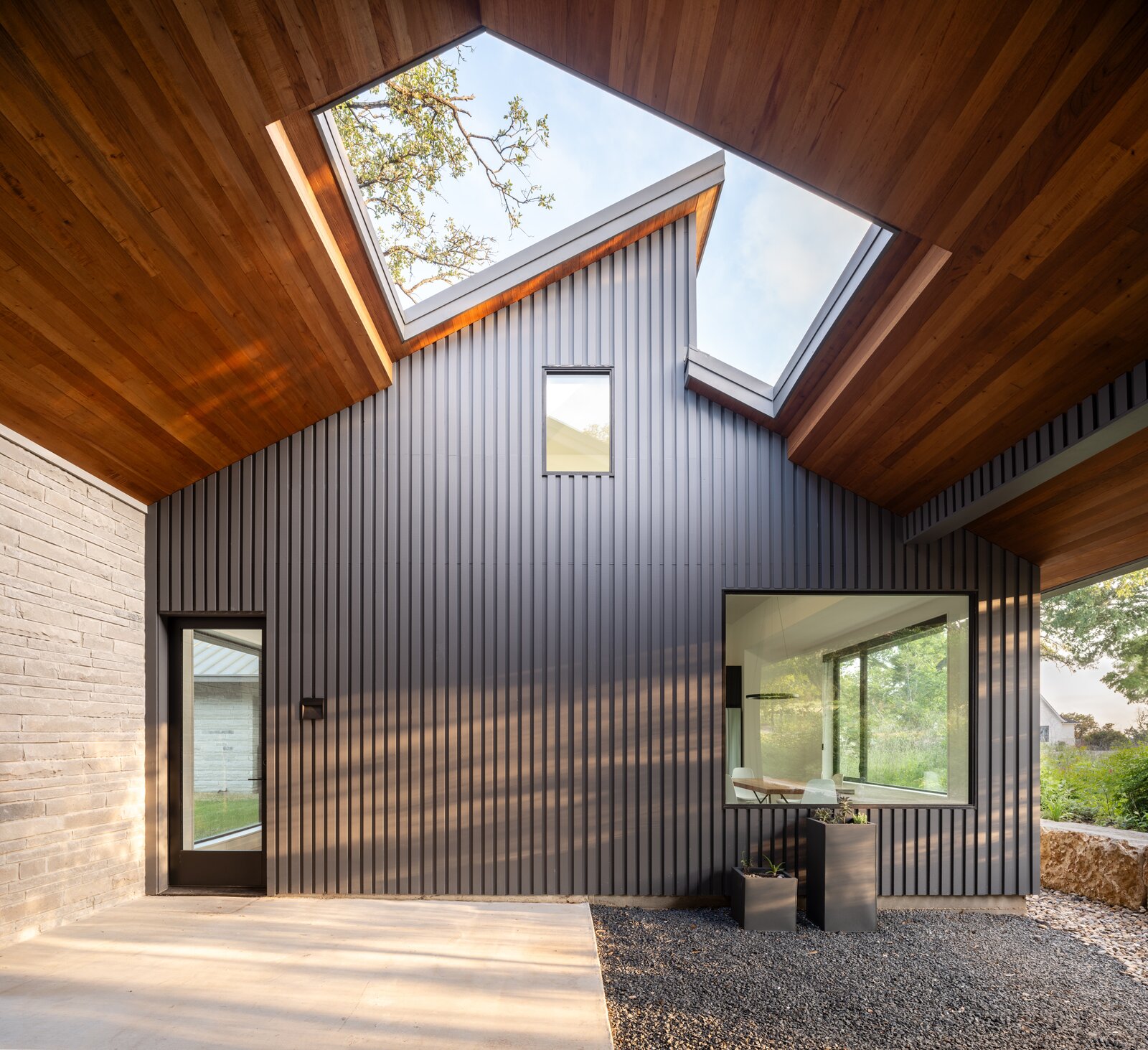 A covered breezeway connects the main house and the guest house. Here, Legge took the opportunity to play with perspective, framing part of a tree and the sky with an abstract roof cutout. 