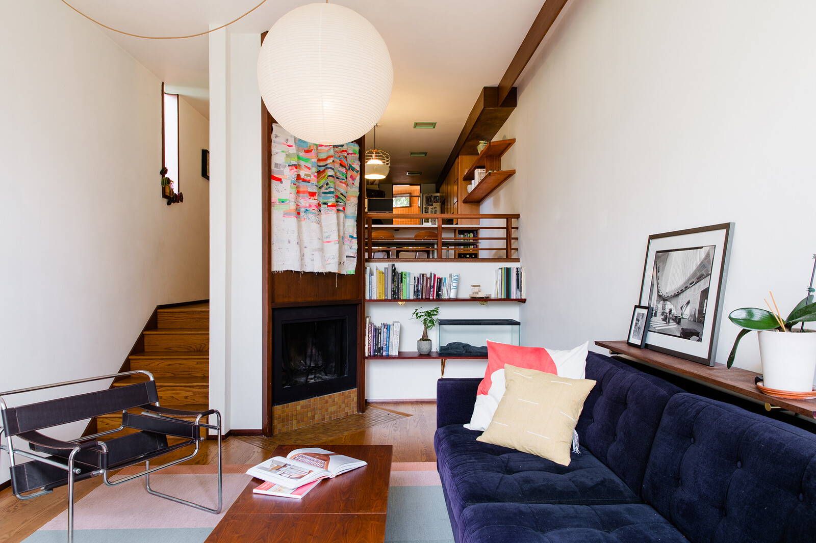 The removal of the money wall opened the kitchen up to the living room below, allowing more natural light into the space. The bookshelves below, where the family's hedgehog lives, and the shelving behind the sofa, are new additions. 