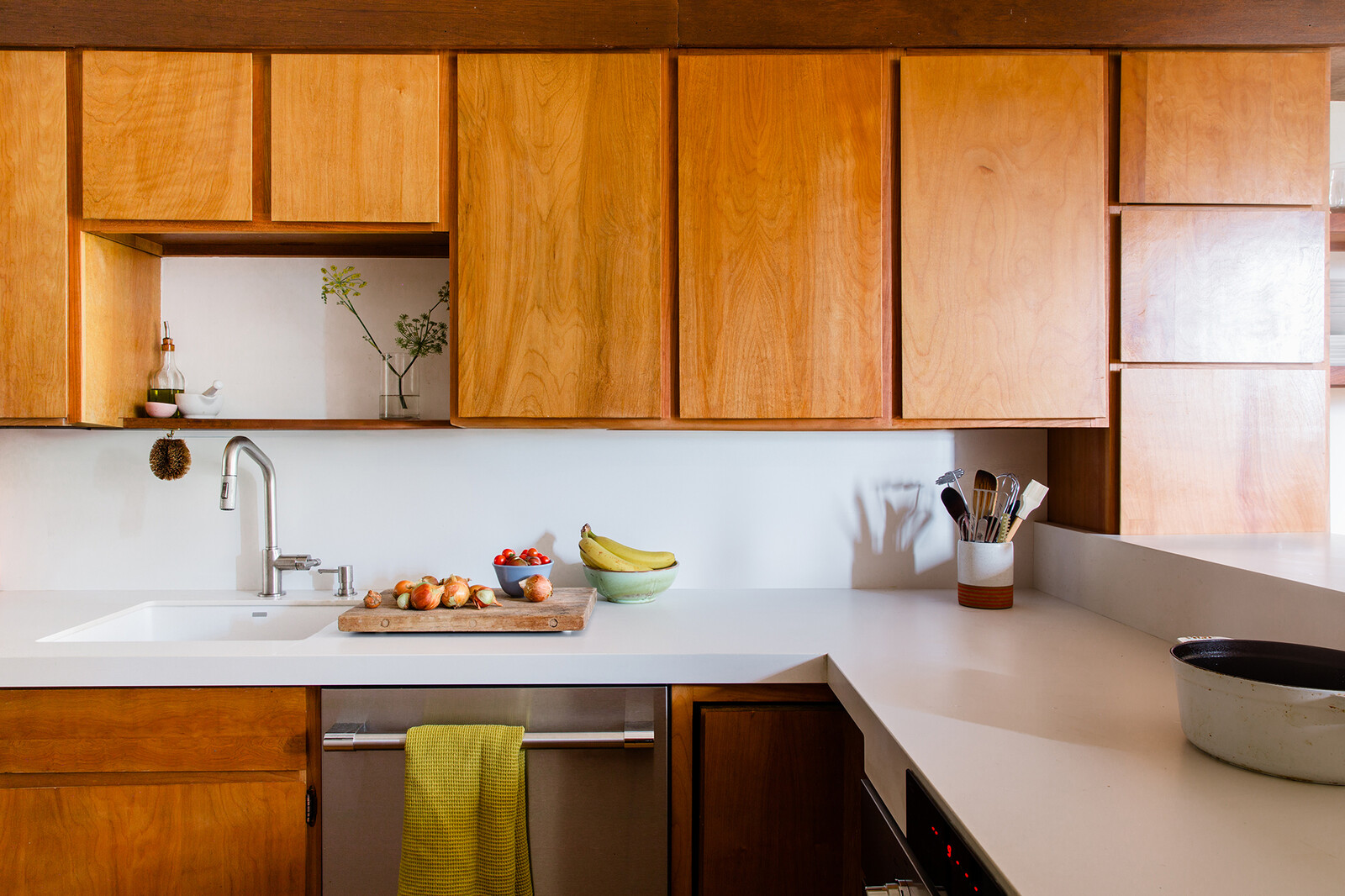 The Invisacook induction range sits beneath the porcelain countertops, giving the couple, who love to cook together, a few extra feet of prep space. The architects removed the original hinges on the cabinets, replacing them with a hidden version that modernizes the look. 