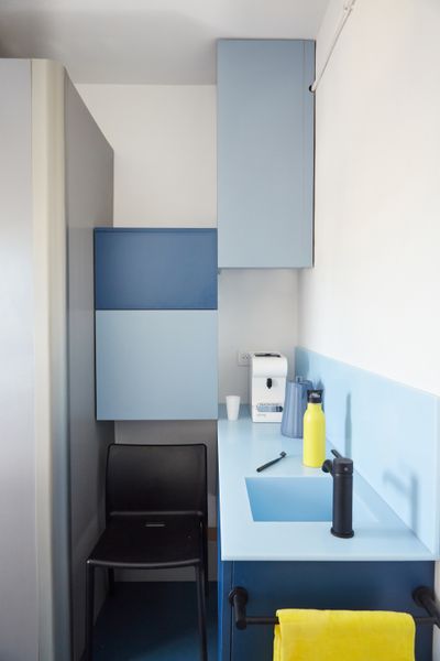 Custom wall-mounted cabinets hide appliances and create storage space in the kitchen area with its Air Chair by Jasper Morrison from Magis.