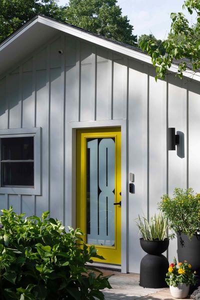 Howmeowner and designer Ghislaine Viñas painted the glass front door's frame in Benjamin Moore's lemon-y hue, Baby Chick. Her graphic designer husband Jaime created the numerical graphic that also serves as a privacy screen.