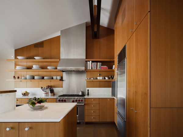 Warm Douglas fir cabinetry, Olympian White Danby marble countertops, and Sub-Zero Group appliances build the contemporary kitchen.