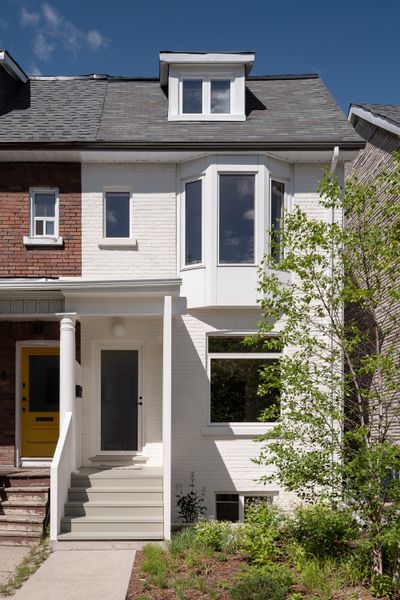 After: White limewash by Romabio gives the reclad and reinsulated brick facade a fresh look and more efficiency. Demolishing half the porch, architect Jon Cummings created a lightwell to pull sunlight through the lower level.