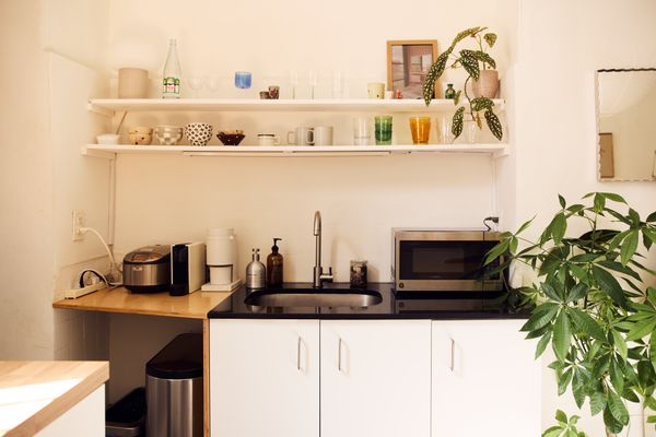 The sink counter cuts off in an awkward way, so Serai built a custom counter extender with plywood, which creates more surface area for appliances. Below, a trash can hides.