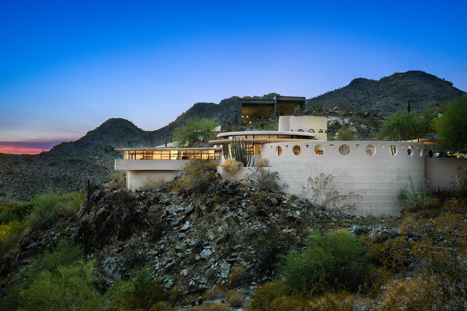 Perched high above Palm Canyon in Phoenix, Arizona, the Norman Lykes House has mahogany walls and built-ins, a curvaceous kitchen, and a crescent-shaped pool.