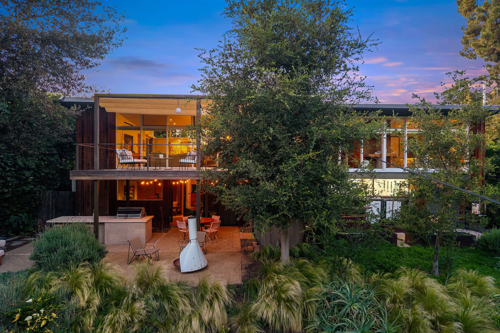 This updated Brentwood midcentury is tucked into a leafy site with an outdoor kitchen, sauna, hot tub, and firepit.