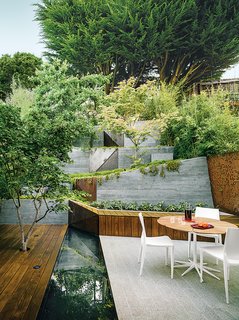 A maple tree grows through an ipe deck in the garden that Mary Barensfeld designed for a family in Berkeley, California. A reflecting pool separates it from a white-granite patio, which is furnished with a Petal dining table by Richard Schultz and chairs by Mario Bellini.