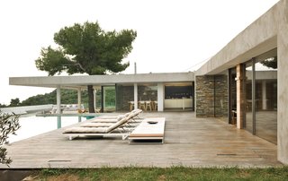 Perched on the mountainside of the Greek island of Skiathos, this midcentury modern-inspired house by Athens-based K-Studio employs stone walls, pine trees, a deep overhang, outdoor rooms, a swimming pool, and endless views of the sea to great effect.