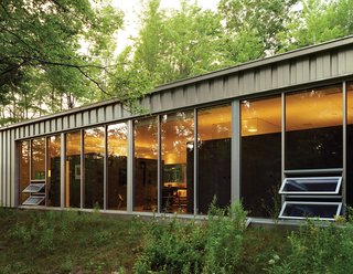 Industrial Revolution - Photo 3 of 7 - Floor-to-ceiling windows capture natural light and warmth while offering expansive views of the woods to the south. "In the winter, I like to use the house as therapy because there’s so much light," Cook says.