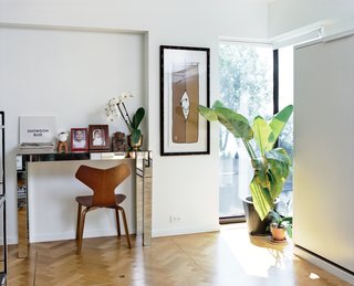 A Renovated Flat in Moshe Safdie's Habitat '67 - Photo 4 of 8 - They restored small alcoves to rooms including the office (shown here) and living room and worked carefully with the existing windows. They also hunted down a craftsman, Marc Ablasou, to install oak floors in a herringbone pattern—a touch that subtly complicates Safdie’s aesthetic. In the office, the mirrored console is vintage and the Grand Prix chair is by Arne Jacobsen for Fritz Hansen.