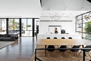 The fourth-floor kitchen of this family home in Tel Aviv features Heracleum II pendants by Bertjan Pot for Moooi that hang over both the kitchen island and the dining table. Eames shell chairs surround the table.