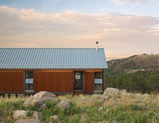 Sustainable Retreat on a Fire-Devastated Site in Boulder - Photo 4 of 7 - The fire-resistant structure is clad in corrugated Cor-Ten steel that has been left to rust for easy maintenance. Instead of fussy landscaping, the family spread seed for native grasses and wildflowers that they let fill in naturally.