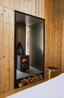 To heat the small structure, Blee and Halligan installed a 17.75-inch-tall, 15.75-inch-wide, and 15.75-inch-deep wood-burning stove equipped with a built-in water boiler. The stove was built into an old doorway that was no longer needed. By wrapping the walls in sheet steel, Blee and Halligan made the area fire-resistant, and the warmth from the stove is amplified as it reflects into the room. Though it's handy in the winter, the stove-boiler combination is merely decoration in the summer: "It's so hot that we just bathe in the river nearby," Blee says.
