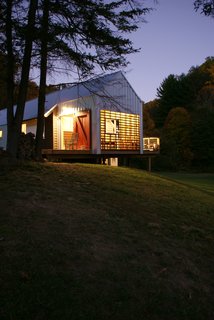 The new home’s porches glow like lanterns at night. Image courtesy Chad Everhart Architect.