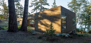 "The liberal use of wood roots the structure in the landscape and provides the owners with an experience strongly connected with location," Herrin says. The exterior’s Western red cedar shingle siding has a semi-transparent stain, half Fieldstone and half Burnt Hickory from Cabot.