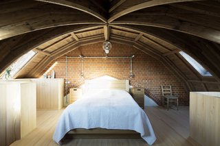 The bedroom is located on a mezzanine just below the roof of the church. The minimal decor and simple arrangement of the room reflect the client’s modest tastes. The small pewter spotlights and pendant by Holloways of London connect to an exposed galvanized conduit that is set against the brick above the bed.