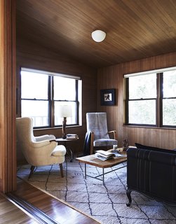 In a 1940 home designed by modernist Joseph Esherick, the interiors are wrapped in hemlock, but the high ceiling, large windows, and plush textiles of the carpet and chairs keep the space fresh, bright, and comfortable.