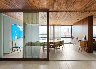 Blockbuster Movies Can't Compete with These Monumental Views - Photo 1 of 9 - A wooden partition separates the dining room from the living room. The jacaranda table is a vintage find designed by Jorge Zalszupin for L’Atelier. The dining chairs are by the Brazilian designer Sergio Rodrigues and architect Isay Weinfeld designed the sideboard. The fluorescent lamp sculpture on the wall is Luz Natural by Eduardo Coimbra.