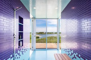 Consider this lively bathroom that sits within a recently completed waterfront home in Bridgehampton, New York. Situated on two-and-a-half acres of land with 360-degree views of the nearby bay and ocean, it's covered with brightly colored floor-to-ceiling tiles that reflect the shades of the neighboring water. One step through the sliding glass doors and you’ll find yourself on an open terrace.