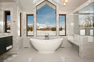 Making our way to Jackson Hole, Wyoming, this master suite bathroom is nestled within a mountain retreat that sits on five acres of private land. Slabs of Carrera marble line the space while the central window overlooks the Grand Teton national park. Placed at the edge of the bathroom is a 50-square-foot shower with steam capabilities.