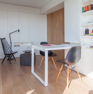 10 Essential Tips For Creating a Hardworking Home Office - Photo 6 of 10 - A sliding oak door leads from the living room to the studio library, outfitted with custom, white-lacquered built-in units and furnishings. The floor lamp is by Marset, and the MDM lounge chair and poufs, all from Materia, form a cozy reading nook.