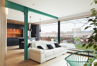 50 Modern Homes With Floor-to-Ceiling Windows - Photo 1 of 50 - The glazing between the living and kitchen areas and the exterior was reconfigured seamlessly to join a terrace surfaced with artificial turf and Nature Teka decking by Disegna. The beam was coated in a shade of turquoise paint that matches the Acapulco chairs.