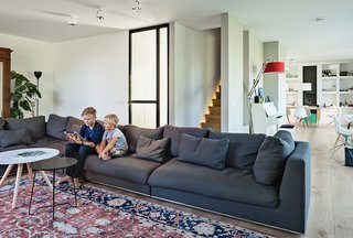 A Modern Take on the Pitched-Roof - Photo 9 of 12 - In the living room, Bram and Dirk sit on a sofa by Cocoon near a Persian rug and tables from Leen Bakker. The architects illuminated one side of the stairway leading to the bedrooms.