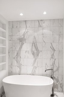 The master bathroom’s Wetstyle bathtub, paired with a Kohler faucet, sits up against calacatta marble tiles on the wall.