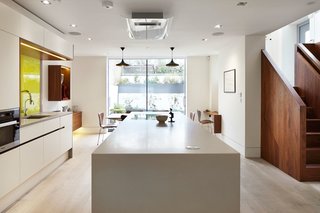 This formerly dark basement kitchen now feels much lighter, thanks to the addition of white oak floorboards, bright plaster walls, and floor-to-ceiling windows that let in garden views.
