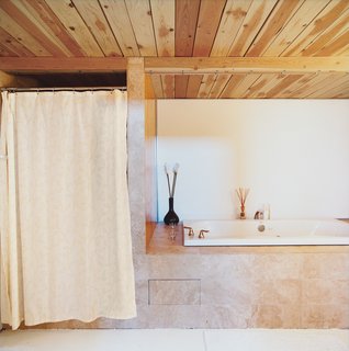 A Minneapolis Building That Has Lived Multiple Lives Is Revitalized by a Coffeehouse Owner - Photo 8 of 10 - The master bathroom departs from the cool tones used throughout the house in favor of warmer, neutral-toned marble tiling, which wraps around a large soaking tub.