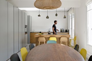 After spending a decade in China, a lawyer and a CEO returned to Paris with their two young children and settled in the city’s 16th arrondissement. However, the 1,000-square-foot apartment’s cozy quarters would soon turn cramped when the couple discovered a third baby was on the way. The adjacent residence and the seventh-floor property above were for sale, so the pair purchased both to connect all the spaces together. "Perhaps the most recurrent request from the client was to create as much storage space as possible, which they desperately lacked in the original apartment," architect Eitan Hammer says. The kitchen’s cabinets provide plenty of room to keep things tidy. Tom Dixon bar lamps hang over the island. 