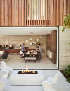 With the home’s glass walls pulled open, the patio becomes an extension of the dining room. A trio of Panton chairs surround a fire pit should guests choose to congregate outside.