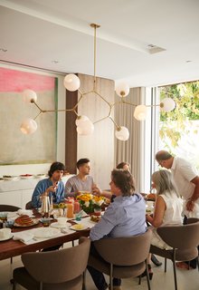 In the dining room, family and friends come together over a walnut-slab dining table from BDDW. The dining chairs are from Minotti, and the Branching Bubble chandelier is by Lindsey Adelman.