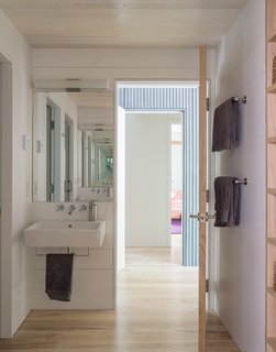 The first-floor bathroom is divided into separate functions so that it can be used by more than one person at a time: the space includes a water closet,a shower, and a larger area<br><br>with a pair of sinks. The towel racks and fixtures are from Kohler.