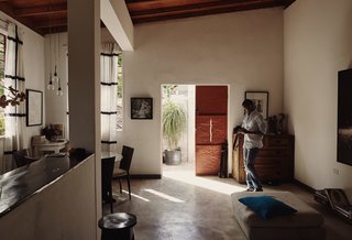 Perimeter walls and distance from the street protects the home’s privacy. Azor made the pendant lights that hang over the dining table. His concrete floors are sealed with Drylok. Azor began with white interiors, experimenting with colors over time before arriving at red for the doors and blue for cushions.