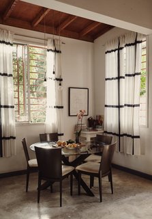 Adjacent to the kitchen, lit by an IKEA pendant light, is a dining area with a table and chairs purchased at a local Port-au-Prince store; the curtains are also from IKEA.
