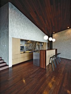 Bamboo plywood is used throughout the house for all integrated furniture, including the kitchen cabinets. The pendant lights are prototypes designed by Jamie McLellan for Tom Dixon and the stools are by Konstantin Grcic for Magis.